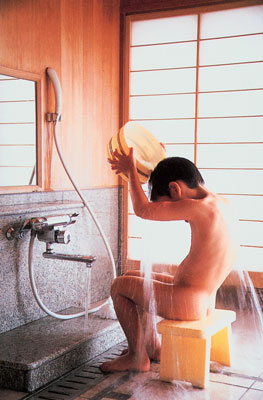 The Japanese bathing ritual has four steps. Seated on a low stool, the bather uses a bucket to rinse away dirt with hot water scooped from the prepared bath, then descends into the tub for a first soak. Reemerging, the bather sits on the stool and scrubs with soap and loofah, then rinses thoroughly. The final step is a relaxing, second soak in the tub. Traditional baths call for an outdoor setting or a room that opens to the outdoors.